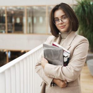 education business and women concept portrait of young attractive elegant female tutor young teacher or student carry studying books and laptop standing in hall smiling camera 300x300